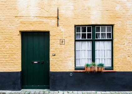 Green door of yellow brick house