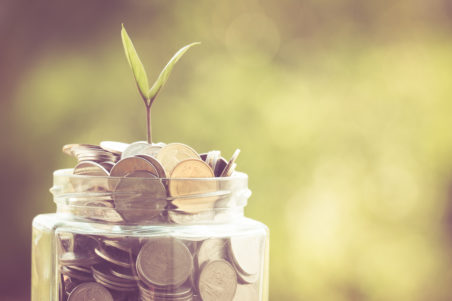 Sprout growing from jar full of coins