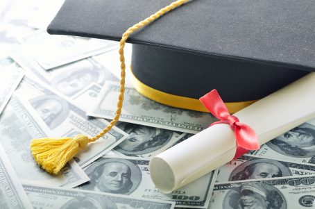 Graduate's cap & diploma on stack of cash