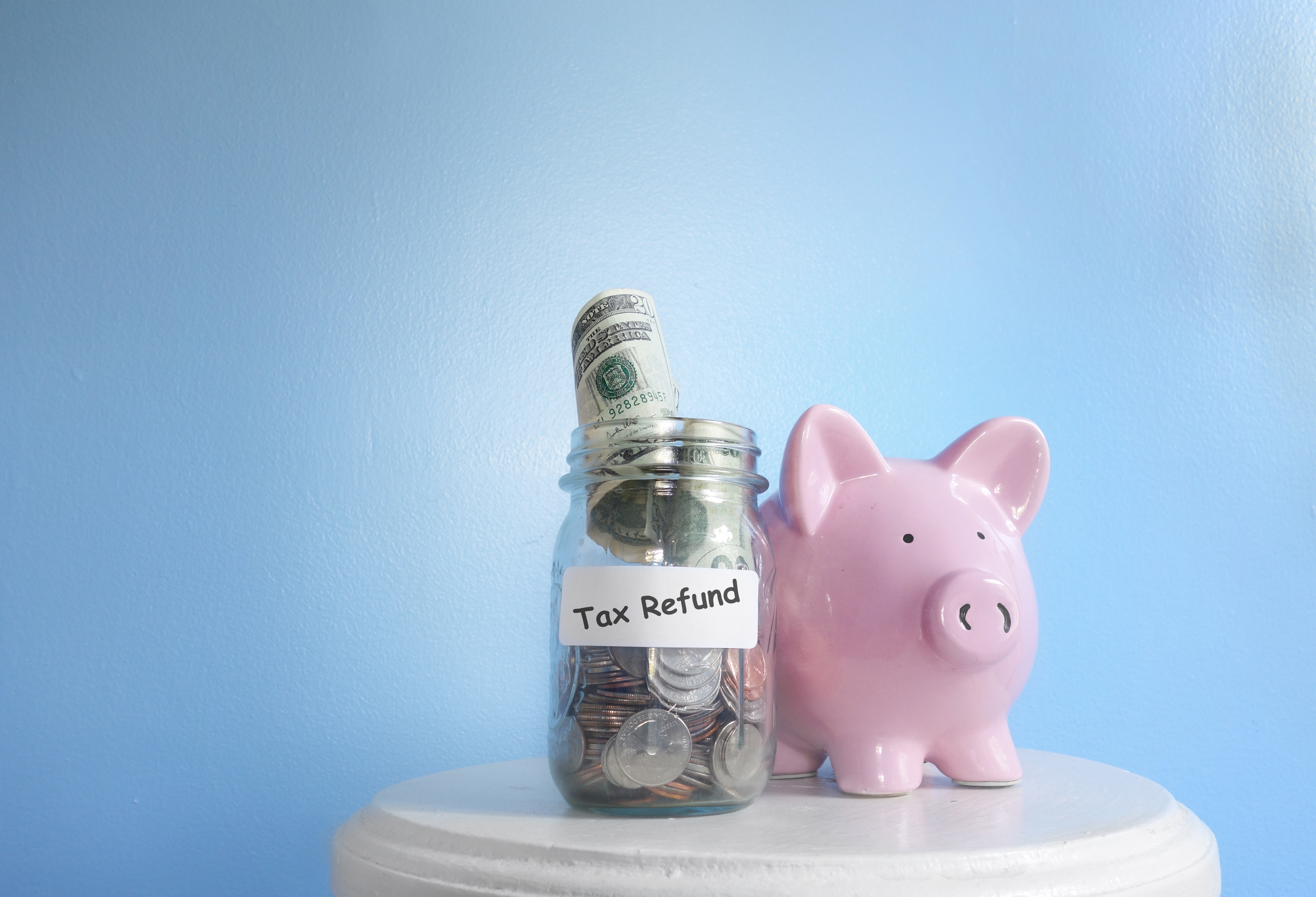 Piggy bank standing near tax refund jar