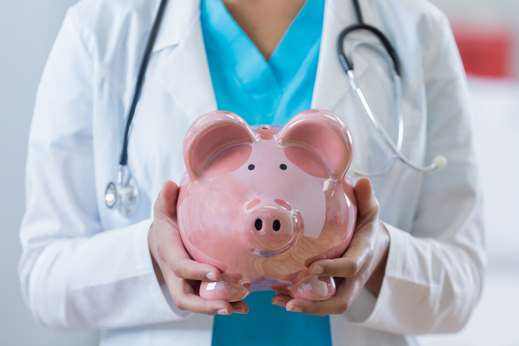 Medical professional holds piggy bank