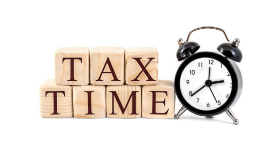 Words "Tax Time" written by wooden cubes with clock on white background.