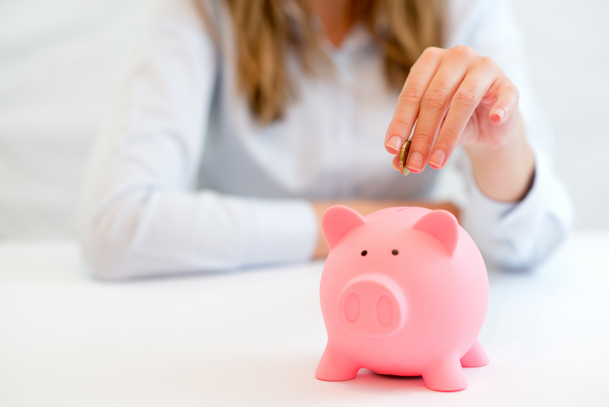 Woman saving coin into piggy bank