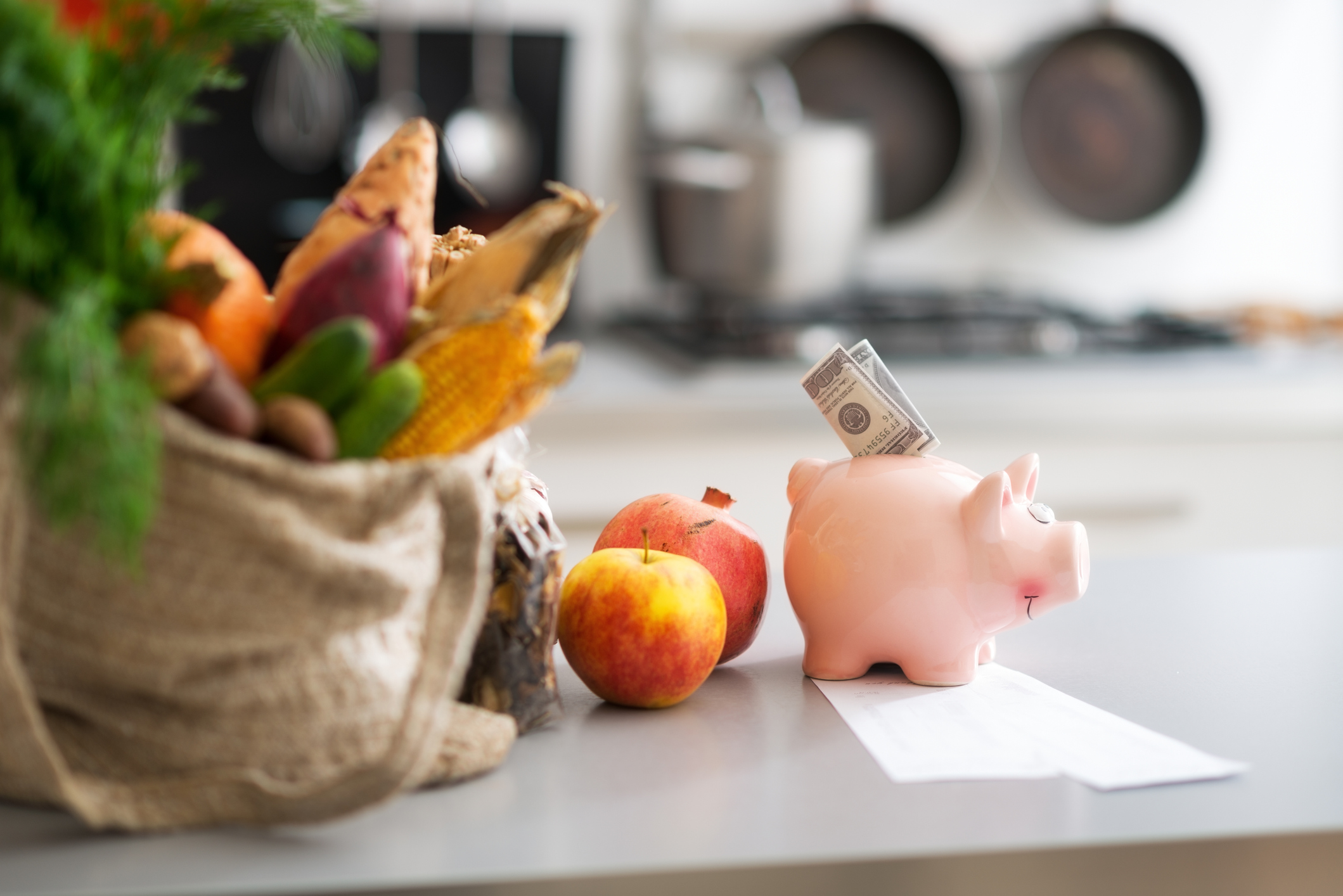 money in piggy bank and purchases from local market on table