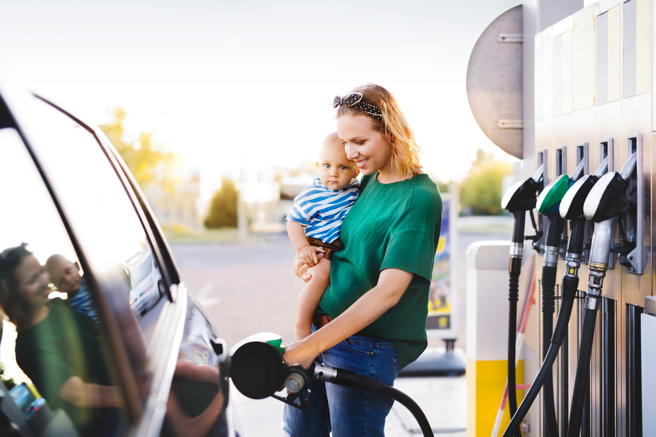mother with baby boy at the petrol station refuelling the car.