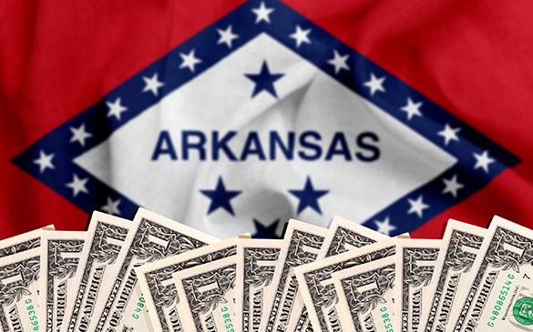 One dollar bills in front of Arkansas state flag