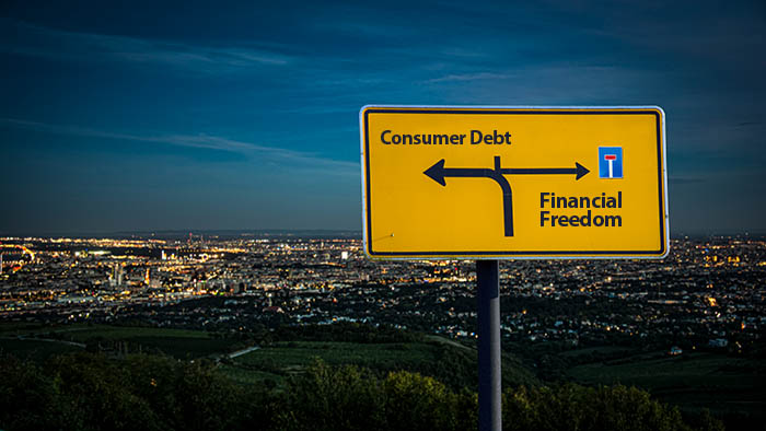 Road sign showing consumer debt and financial freedom in opposite directions